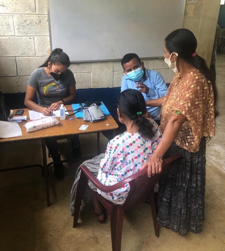 Maria, seated, receives healthcare services in Guatemala from a mobile medical clinic